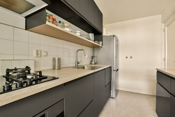 a kitchen with black cabinets and white tiles on the wall behind it is an open door that leads to another room