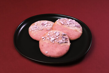 Pink cookies with lavender flavor in a black plate on a burgundy table. Close-up