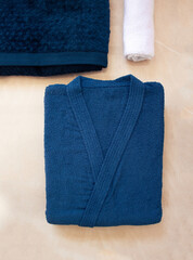  Composition with a folded bathrobe and bath towels. Blue bathrobe on beige background. Flat lay, top view. Bath concept. - obrazy, fototapety, plakaty