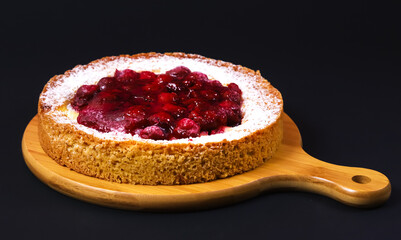 Pie with raspberry jam and powder on a wooden board. Close-up