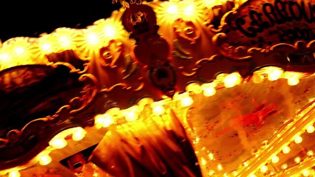 children's retro carousel fun rotates in a dark park, decorated with light bulbs, decorations, spinning merrily, fairground attraction in park with horses for children, concept of holiday, Christmas