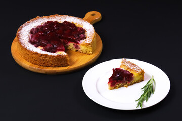 Sliced portion of raspberry pie in a white plate on a dark table. Close-up