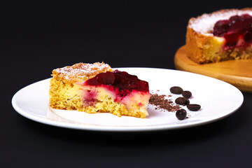 Sliced portion of raspberry pie in a white plate on a dark table. Close-up