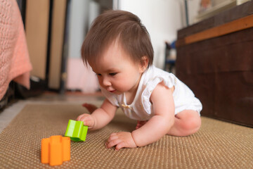 lifestyle home portrait of adorable and beautiful Asian Caucasian mixed baby girl playing on the floor with color blocks excited and happy in childhood concept