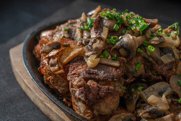 Baked chicken livers and potatoes with garlic, herbs, and fried onion in a cast iron skillet