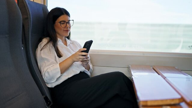 Young beautiful hispanic woman smiling using smartphone sitting at train station