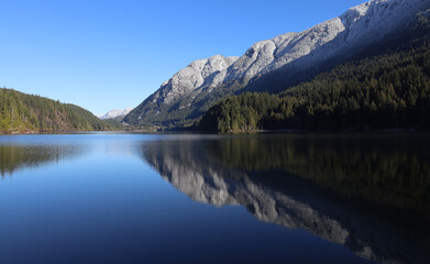 Naklejka na ściany i meble Reflection of snow-covered mountain range in the lake