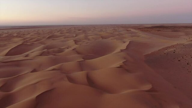 spectacular aerial shot traveling in and at sunset over the sand dunes