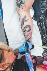 Fototapeta na wymiar top-down shot of a tattoo artist drawing a big snake on a customer's leg, tattoo making concept. High quality photo