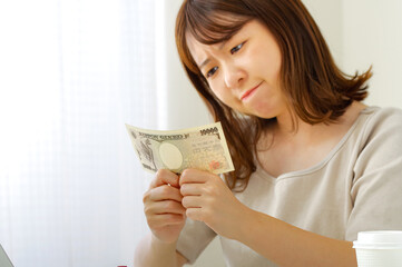 お金を見つめる若い女性