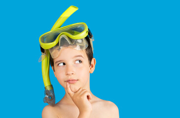 Pensive child with snorkel mask tuba and snorkel looks away at copy space thinking isolated on a...