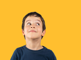 Little boy with blue shirt over isolated yellow background looking away to side with smile on face, natural expression. Laughing confident.