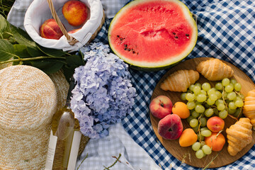 Breakfast picnic with croissants, fruits and flowers on a blanket on a sunny day. Picnic, food,...