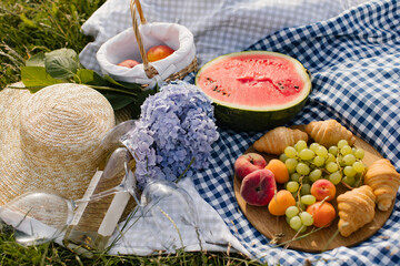 Fototapeta na wymiar Breakfast picnic with croissants, fruits and flowers on a blanket on a sunny day. Picnic, food, brunch, summer mood.