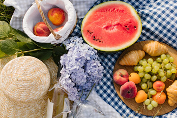 Obraz na płótnie Canvas Breakfast picnic with croissants, fruits and flowers on a blanket on a sunny day. Picnic, food, brunch, summer mood.