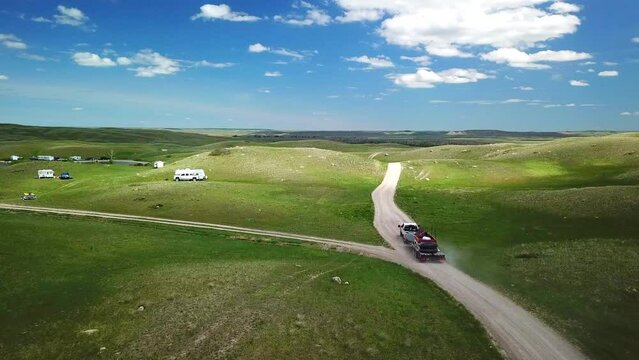 Aerial: Drone Flying Forward Over Pickup Truck With Trailer On Dirt Road Near Lake Against Blue Sky - Billings, Montana
