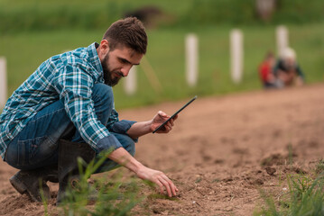 Male farmer plantation checking quality by tablet agriculture modern technology concept smart farming agronomist checking soil quality on the field. - obrazy, fototapety, plakaty