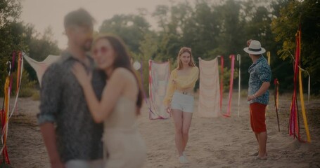 Young couple dancing near friends embracing at beach - Powered by Adobe