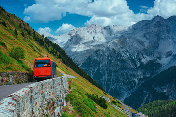 Red touristic bus riding at Swiss Alps mountains in summer