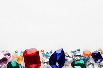 Different beautiful gemstones for jewelry on white background, top view. Space for text