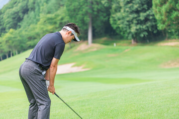 ゴルフ場でアイアンショットをするゴルファーの男性
