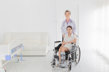 Fototapeta na wymiar Asian patient sitting on wheelchair, patient wear air cast walking boot, doctor and patient talk about symptoms and treatment plan, rehabilitation activity