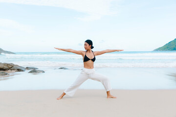Fototapeta na wymiar A happy woman wearing a bikini finds inner serenity as she practices yoga on the beach, embracing the soothing vibes of the coastal environment.