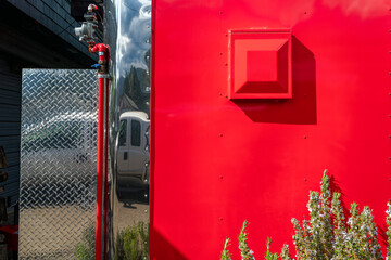 The back wall of a red metal food truck with a vent and gas supply line