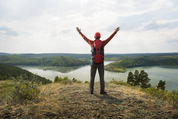 Man traveler on mountain summit enjoying nature view with hands raised. Travel lifestyle wanderlust adventure concept summer vacations outdoor