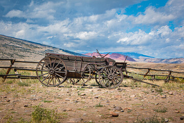 Historic wooden wagon, scenic views of the mountains, and blue sky with clouds, Wyoming, USA