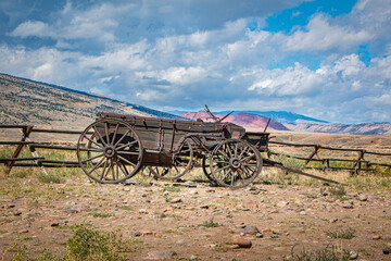Fototapeta na wymiar Historic wooden wagon, scenic views of the mountains, and blue sky with clouds, Wyoming, USA