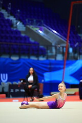 gymnastics and ball between legs of performance, competition training or dancing in dark sports arena. Female athlete, rhythmic movement and creative talent in solo concert, agility or balance