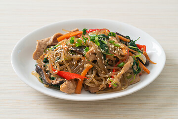 japchae or stir-fried Korean vermicelli noodles with vegetables and pork topped with white sesame
