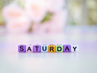 Saturday alphabet letters with blurred pink flowers