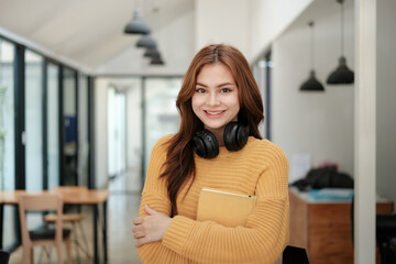 Portrait of beautiful smiling woman. Young student on yellow shirt with head phone standing in the reading room.
