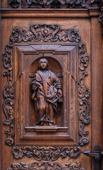 Fototapeta na wymiar Fragment of a page door with beautiful wooden symbols and carvings. Beautiful historical wooden door from the old town of Tallinn, Estonia