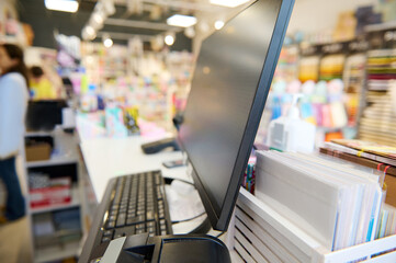 Partial view of a currency counter, note counting machine and PC monitor on the reception desk in school stationery shop