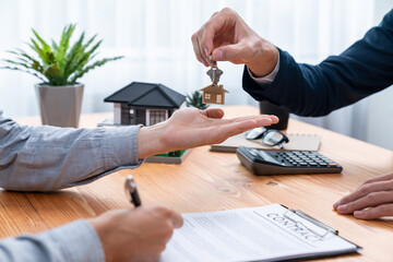 Real estate agent handing house key to buyer after signing rental least contract during house loan meeting. Successful property sale purchase agreement for new home ownership. Entity - obrazy, fototapety, plakaty