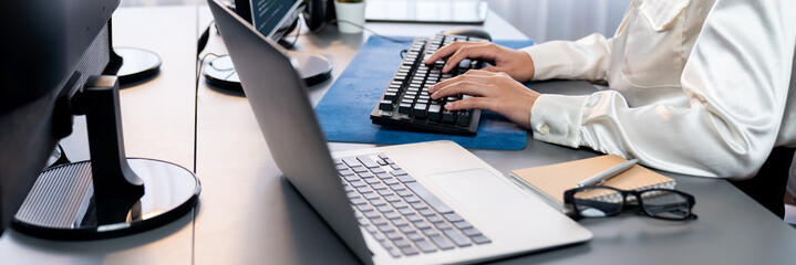 Office worker sitting on workspace desk, focused and engaged, using computer and typing on keyboard...