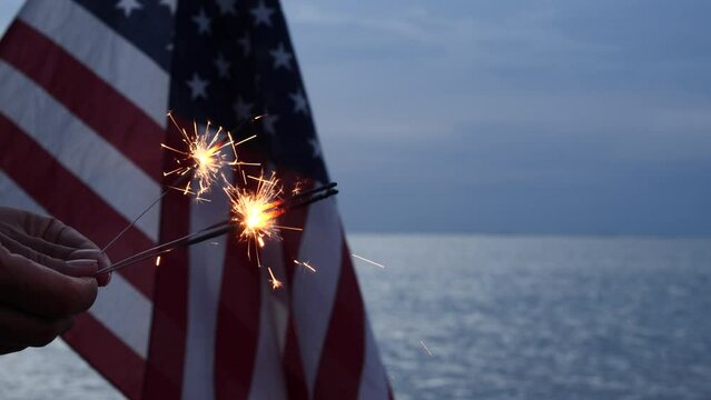 Holding Sparkler Firework Celebration with USA American Flag, outdoor dark background. Concept Veterans Day, Remembrance Day, fourth of July, Freedom, Independence Day. Celebration Fireworks sparklers
