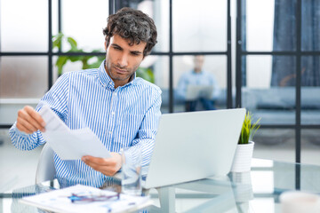 Entrepreneur opening an envelope in a desktop at office. Collegue is on the background.