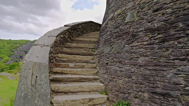 Handheld POV ascending the exterior stone spiral stair steps leading into Dolbadarn Castle, on a spring afternoon, in the town of Llanberis, Wales, UK