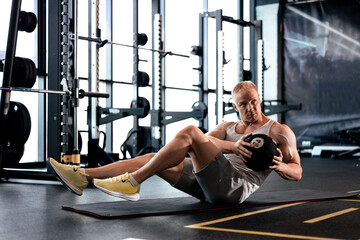Fit and muscular man exercising with medicine ball at gym.