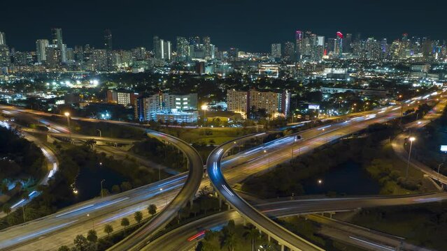 Above view of wide highway crossroads in Miami, Florida at night with fast driving cars. Time lapse of USA transportation infrastructure