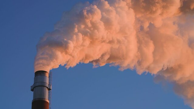 Hot Glowing colorful Smoke Plume sunlit while emitting Greenhouse gas into atmosphere during late evening from Paper mill Industry at Pitea Sweden.