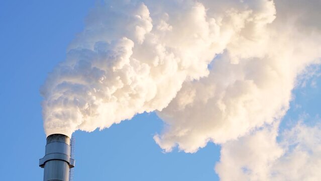 Hot Glowing colorful Smoke Plume sunlit while emitting Greenhouse gas into atmosphere during late evening from Paper mill Industry at Pitea Sweden.