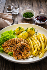 Grilled chicken breasts with yellow beans and boiled potatoes on wooden table
