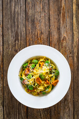 Tagliatelle with broad bean, chanterelle mushrooms and parmesan cheese on wooden table
