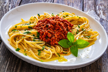 Linguine with minced pork meat in tomato sauce  with parmesan cheese and basil leaves served on wooden table
