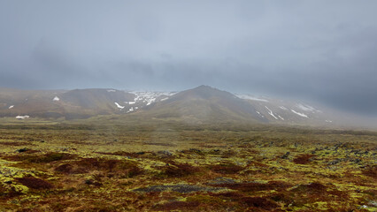 Cloud cover mountains in the middle of Tundra landscape in Iceland .